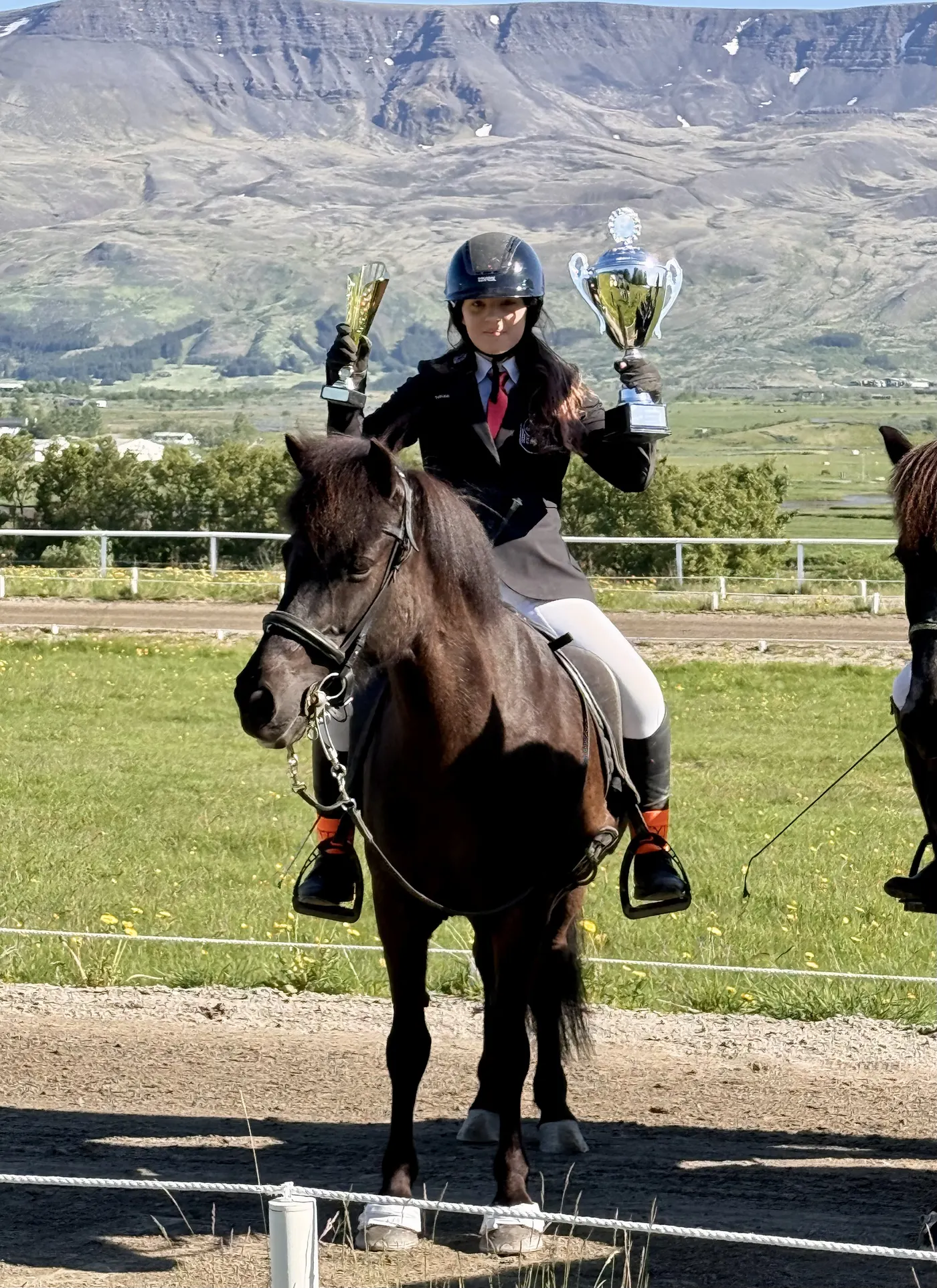 Ungur knapi heldur á verðlaunabikar á hestbaki